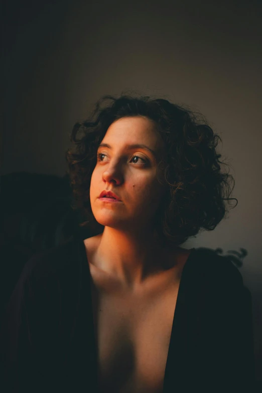 a woman in a black top sitting down with dark hair and blue eyes