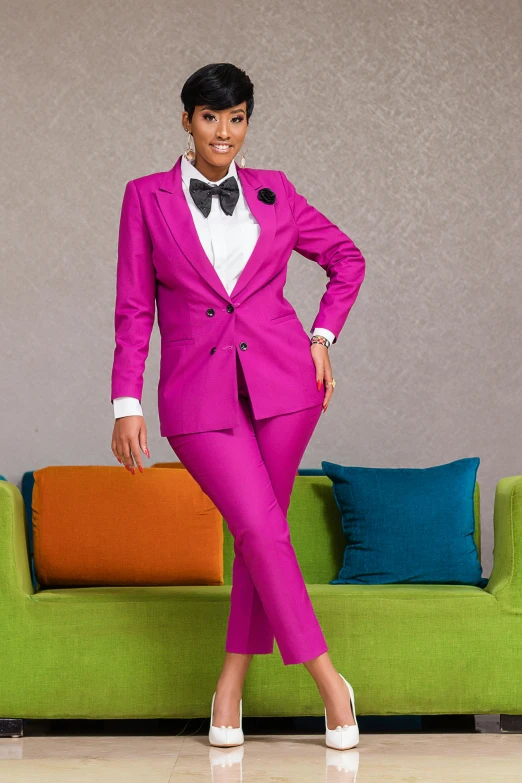 a woman wearing pink suits posing in front of a sofa