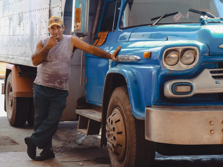 a man leaning on the front end of a blue truck