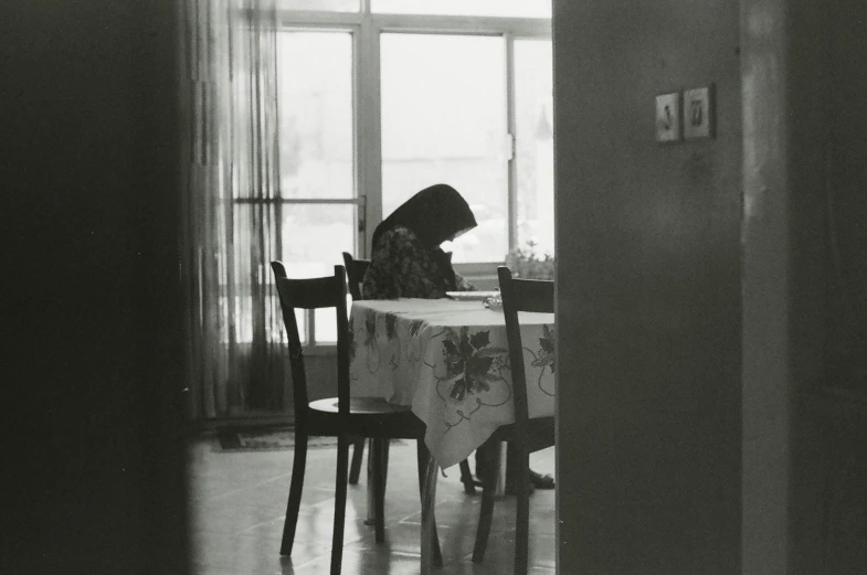 a woman sitting at a table looking down at a notebook