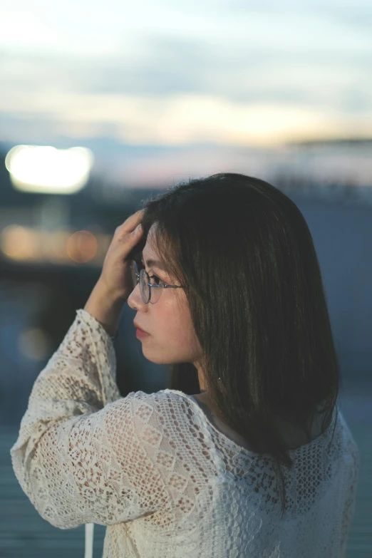 a woman in white sweater sitting with her hand on her forehead