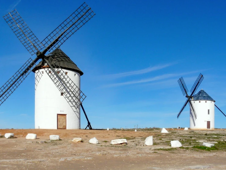 three windmills against a blue sky at the ocean shore