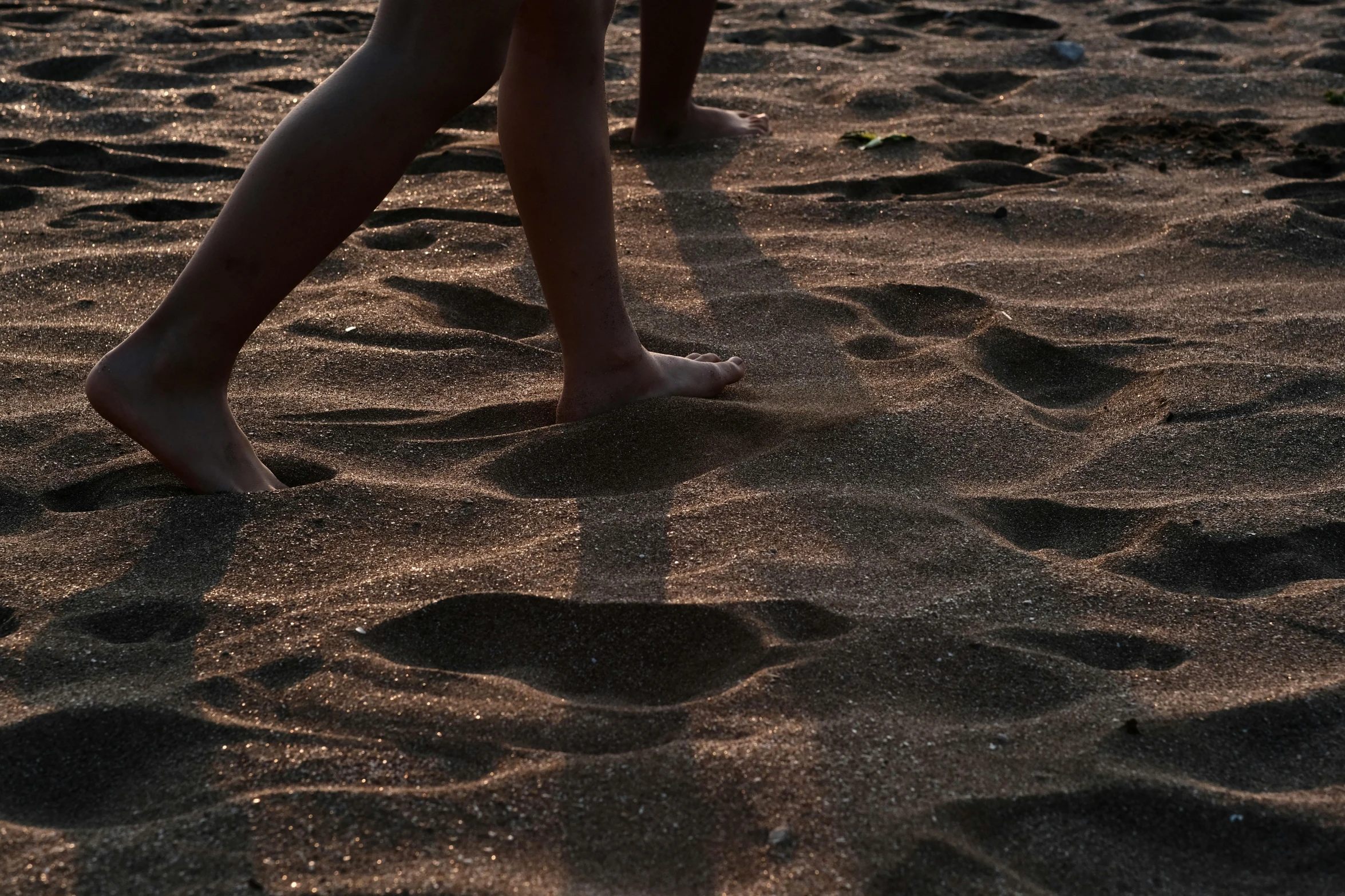 two people walking through sand on a beach