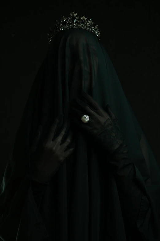 the back of a woman wearing a black veil, black gloves, and white ring