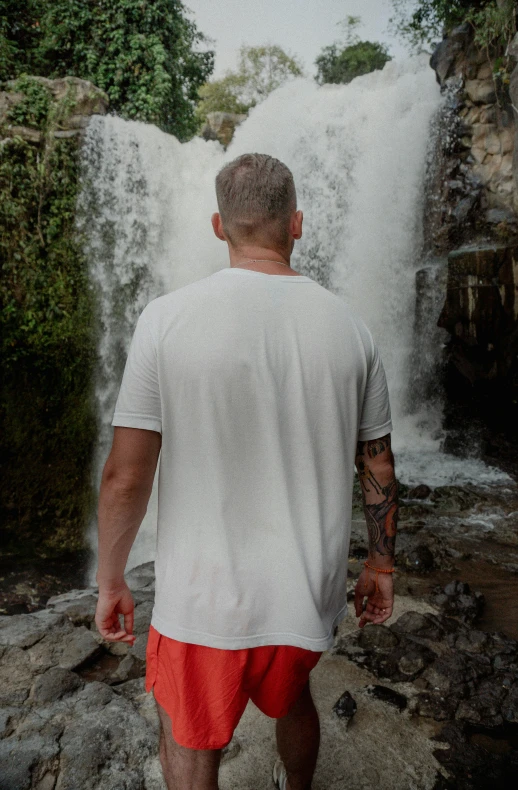 a man walks towards a waterfall in red shorts