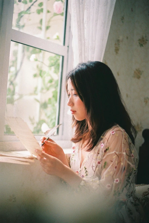 the girl sitting by the window writes a piece of paper