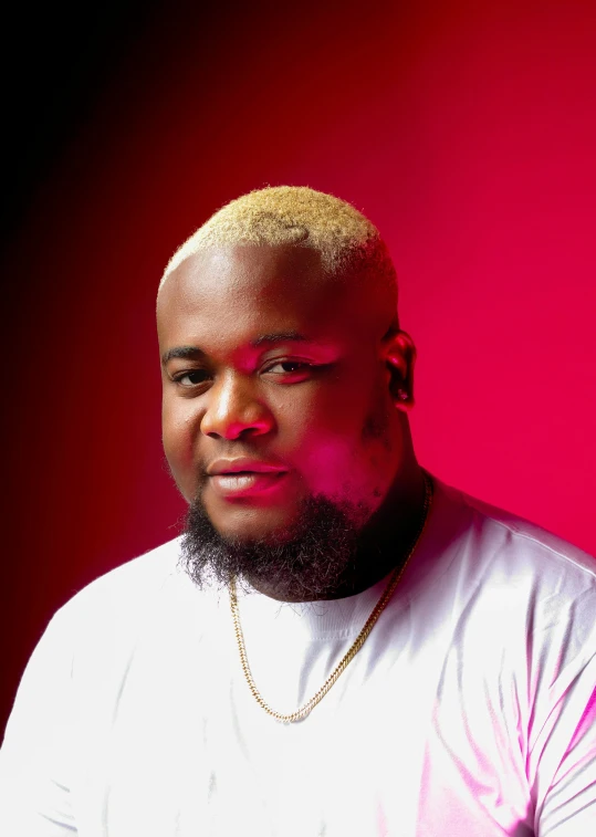 a black man with a pink shirt and necklace