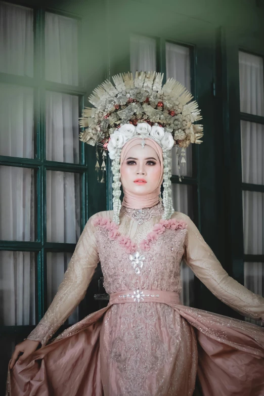 a woman with a dress and headpiece in front of a window