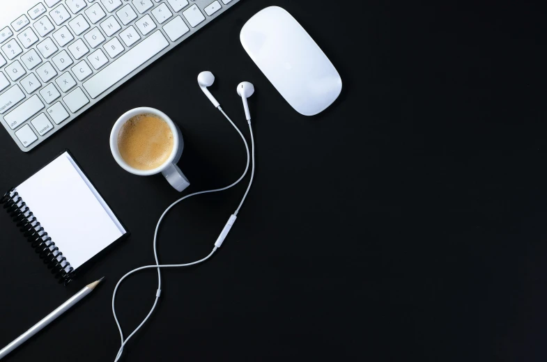 a keyboard, mouse, headphones and cup of coffee