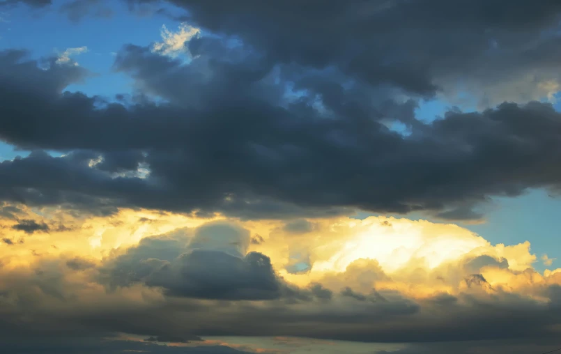 the clouds are dark over the mountains as the sun sets