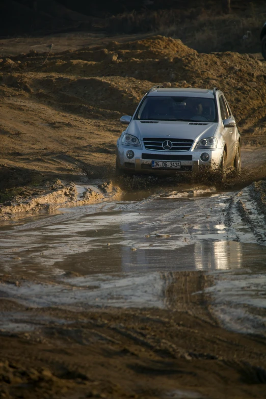 a small white car driving through a body of water