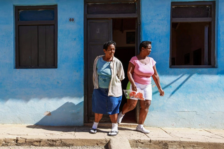 the two women are standing outside the blue building