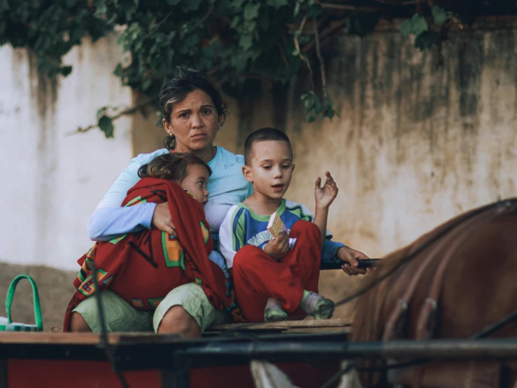 two children and an adult sitting on a cart