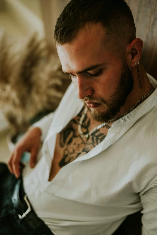 a tattooed man sitting with his cellphone