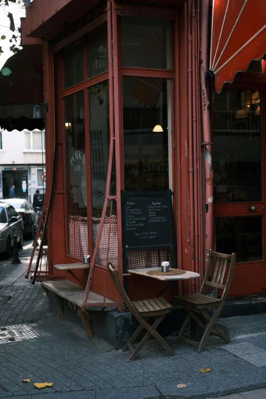 some chairs are outside a red building with a sign