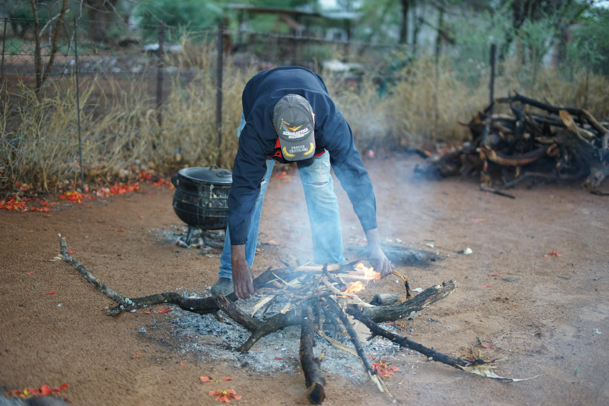 a man bent over grilling soing on top of a pile of wood