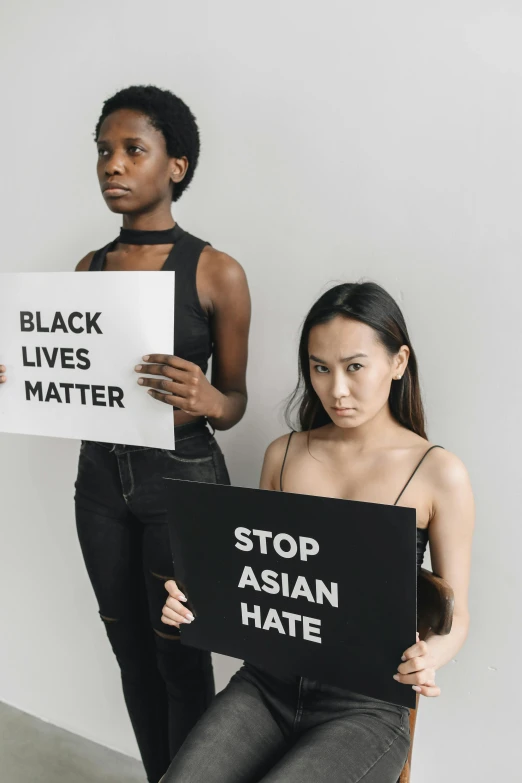 two women holding signs that say stop asian hate