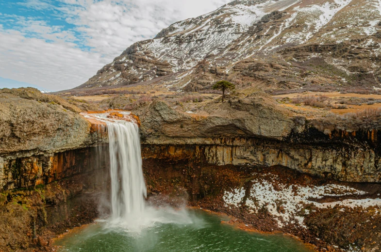 waterfall is flowing down a mountain into a body of water