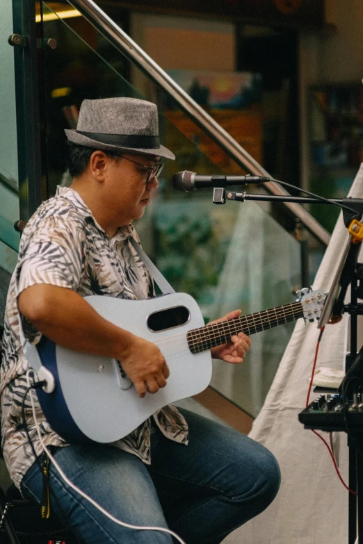 a man sitting and playing a guitar next to microphone