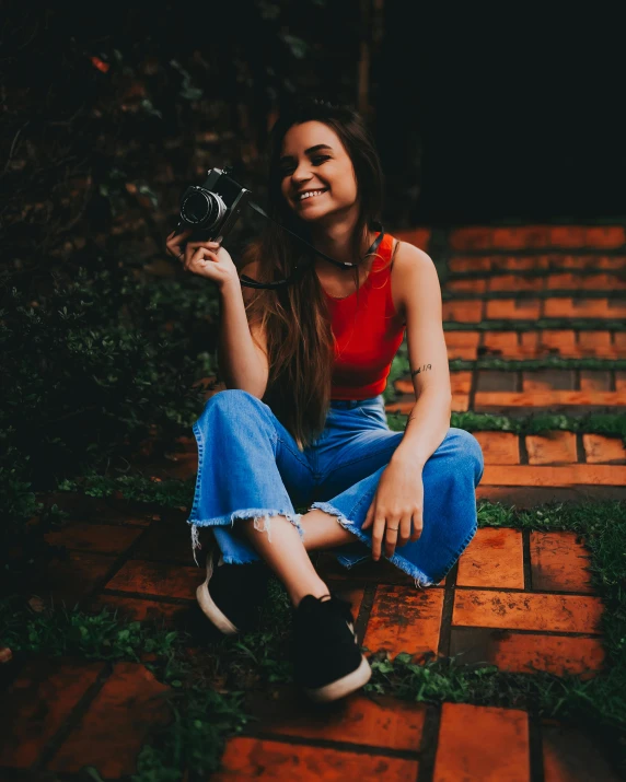 a woman sits on the ground, holding a camera