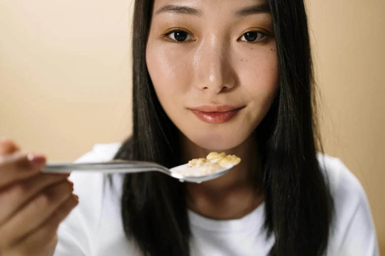 the girl is eating cereal out of a spoon