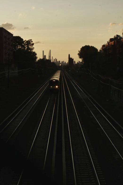 train on tracks at sunset with city in the background