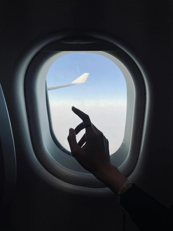 there is a hand on the window of an airplane