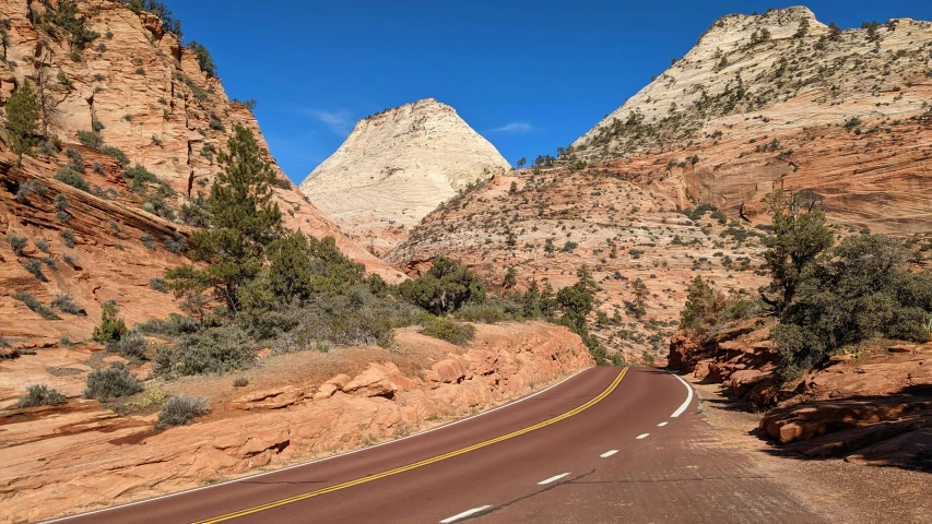 a long road cuts through some mountains on a sunny day