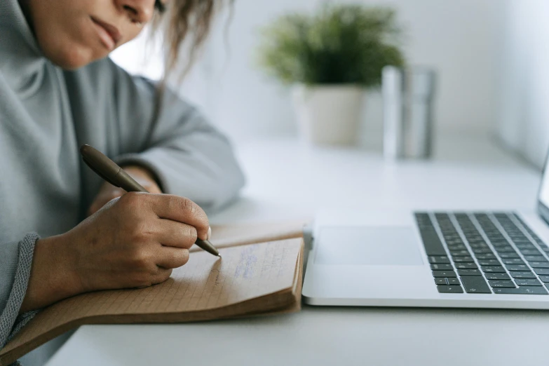 an asian woman is writing on a notebook