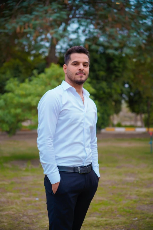 a man standing in a park wearing a white shirt