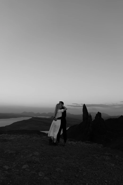 couple on top of hill, kissing by the sea