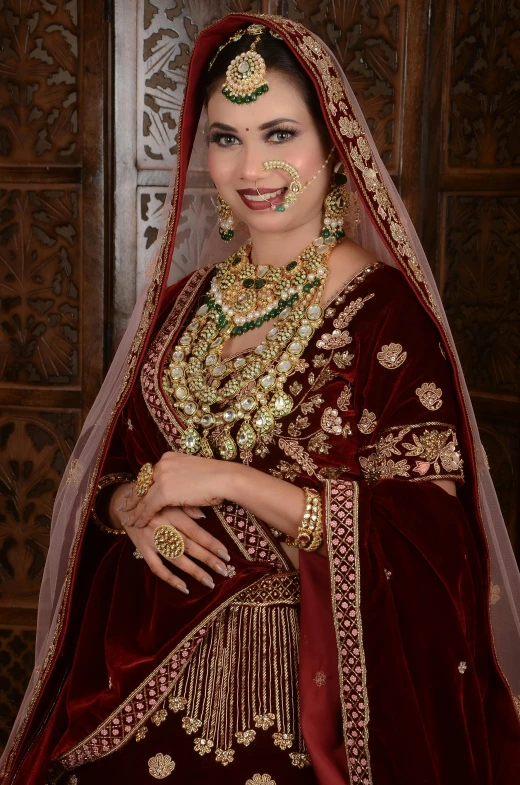 a woman wearing gold jewelry stands in front of a wooden wall