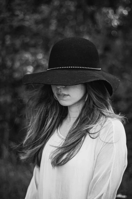 a beautiful woman standing in the woods wearing a hat