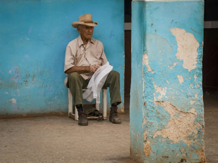 an older man with hat sitting down and reading