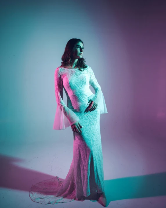 a woman poses in a gown with pink and turquoise lighting