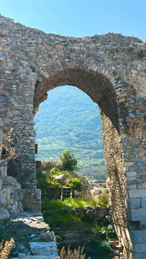 a stone arch that is in the middle of some land