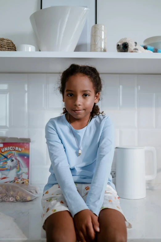 a young child sitting on top of a counter near books