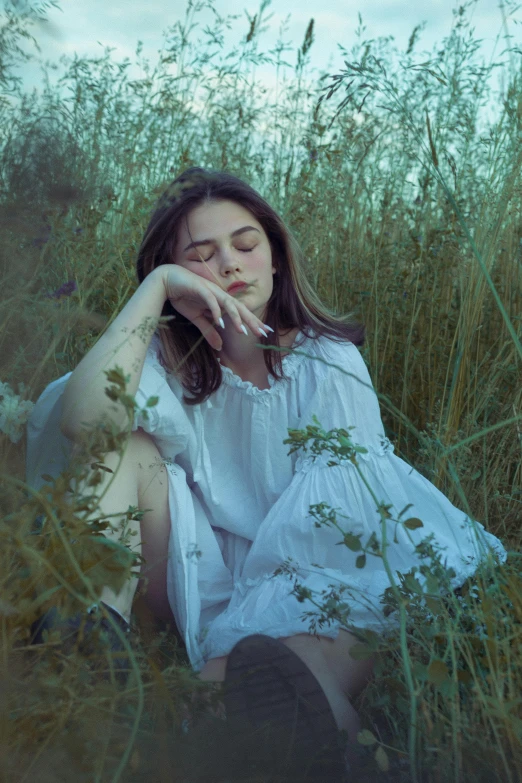 a woman sits in a field of tall grass