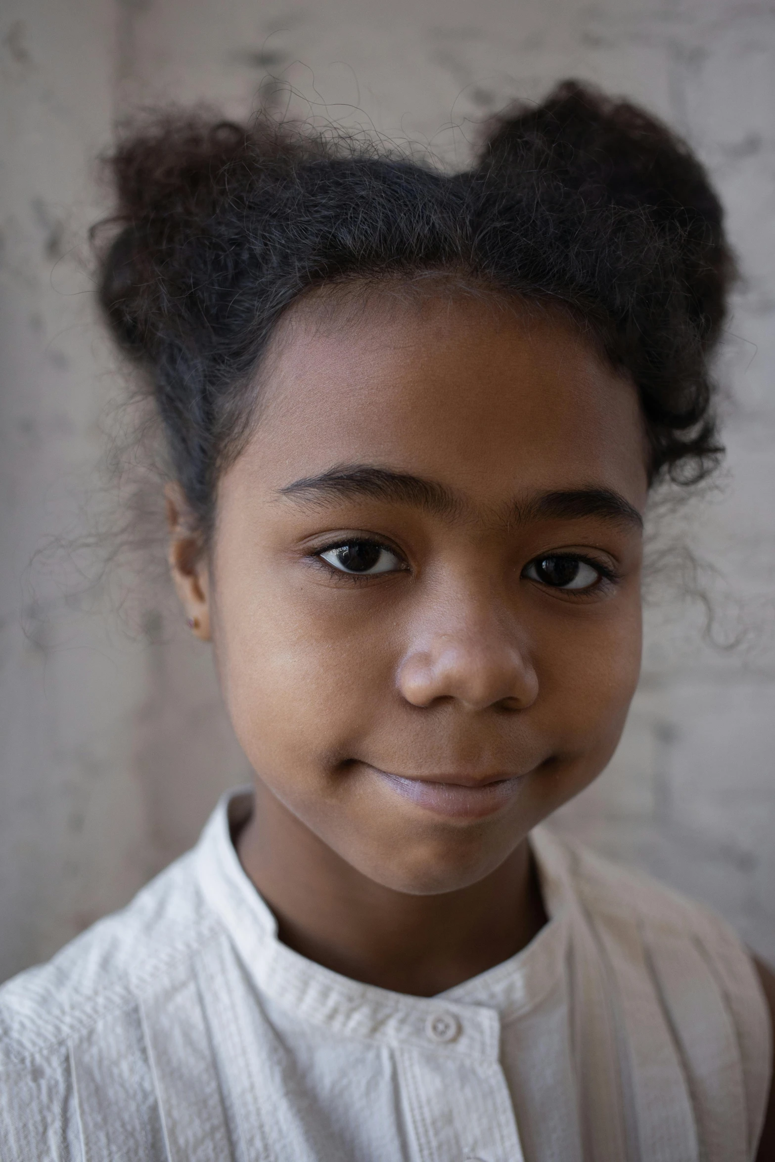 there is a little girl with a big hairdo in front of a wall