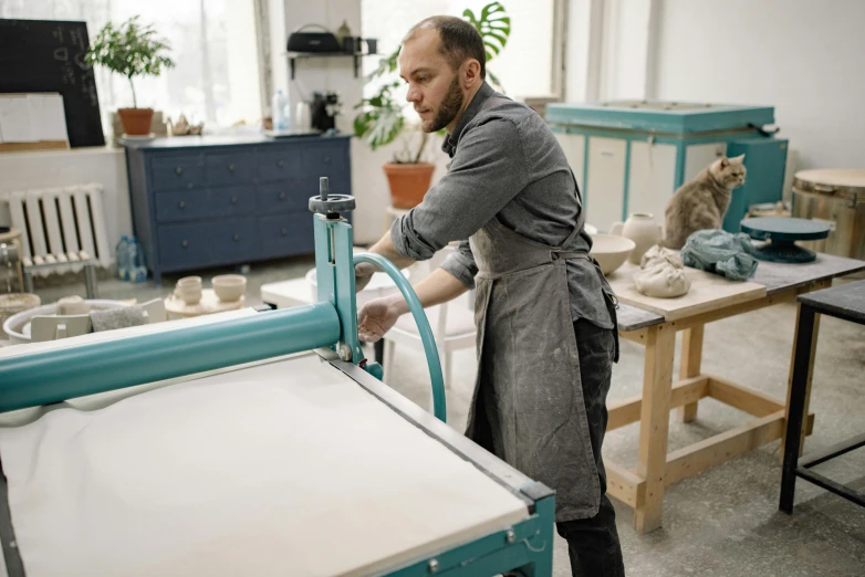 a man in the kitchen with a cat looking down