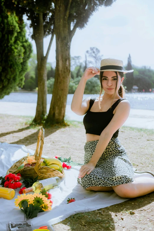 woman wearing hat sitting on grass near baskets and flowers