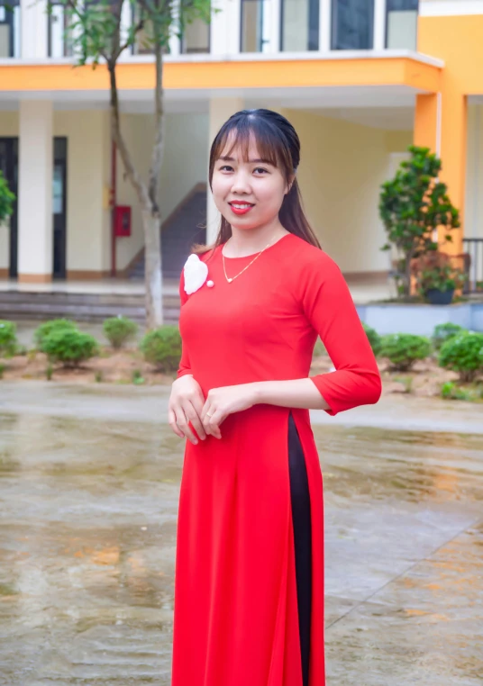 a woman in a long red dress with a heart shaped flower on her sleeve