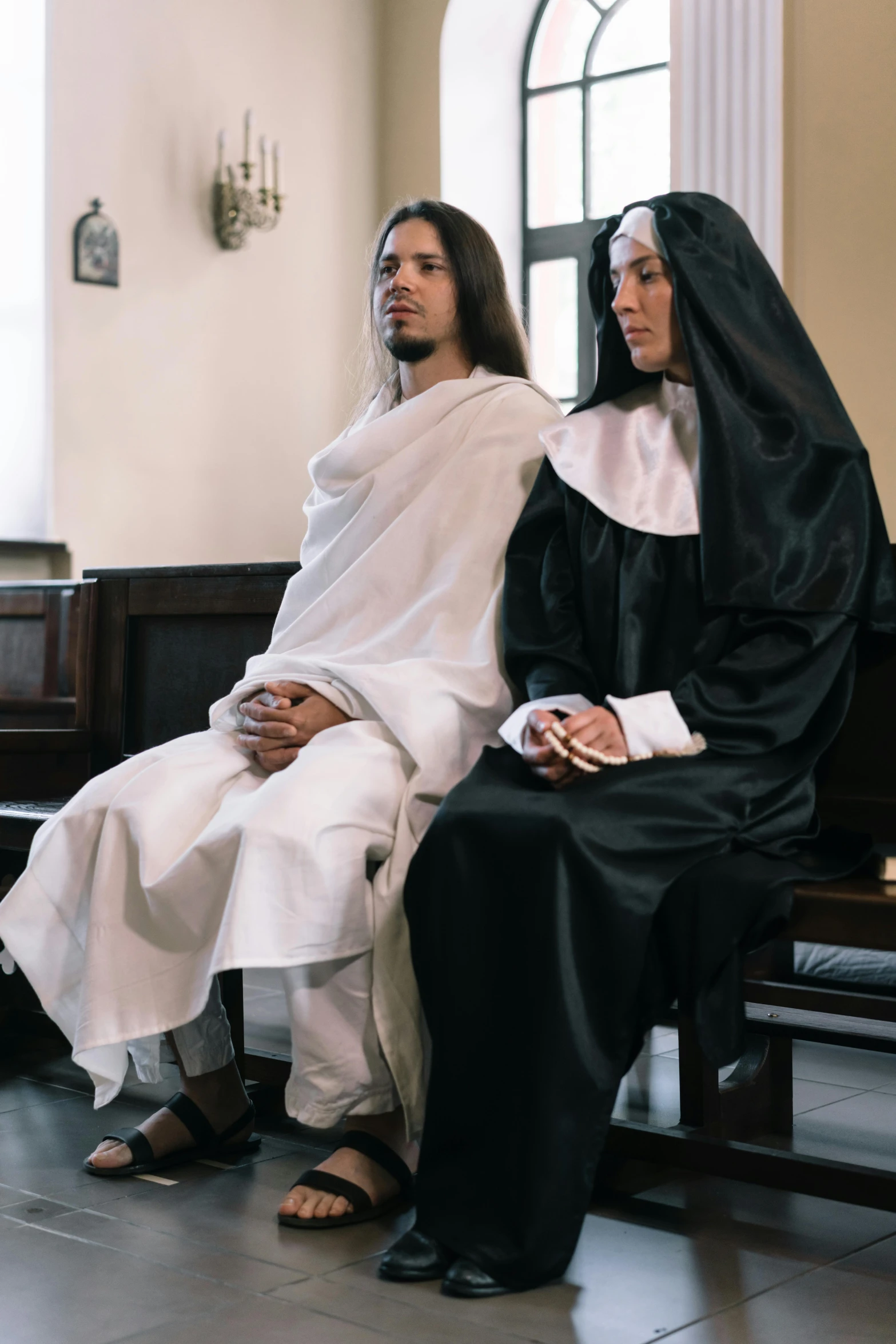 two priests in black robes sit next to each other