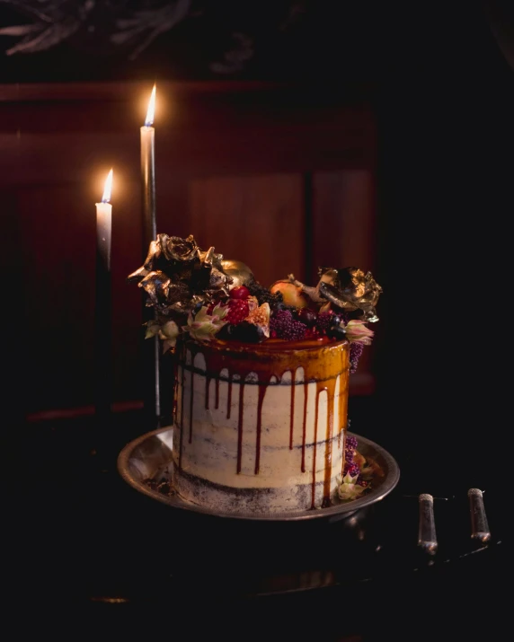 a small white cake with chocolate and flowers with a candle