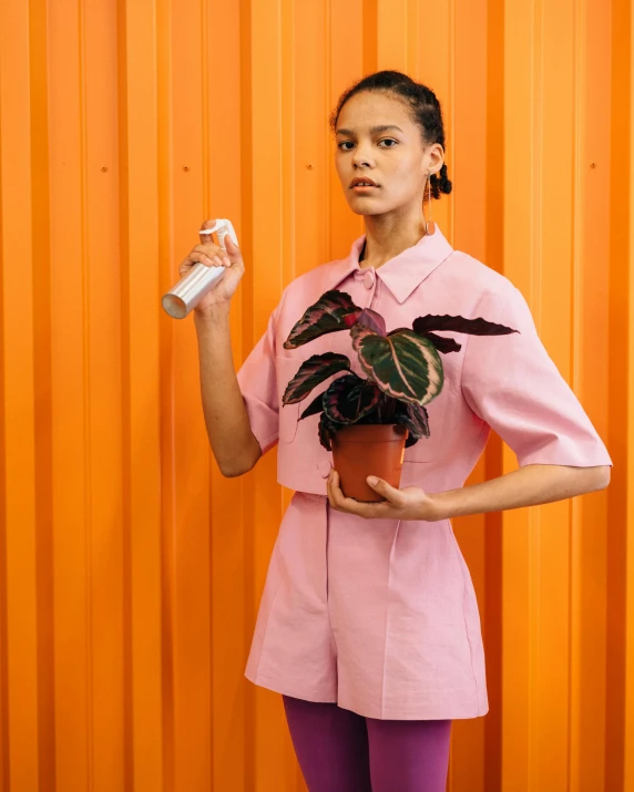 a woman in a pink dress holding a potted plant