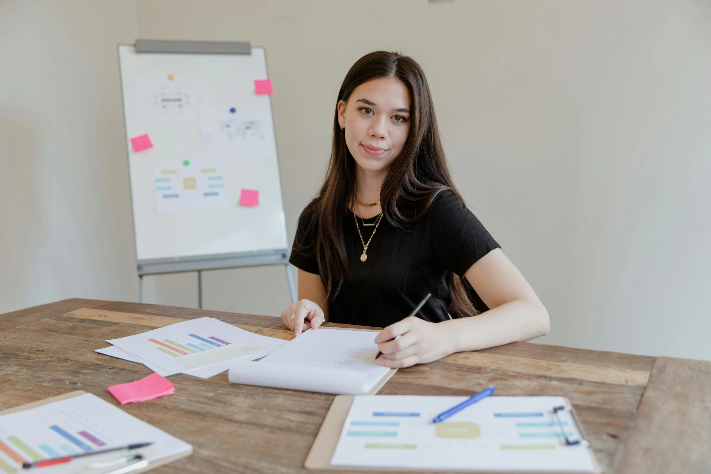 a woman in a black shirt and some papers and pens