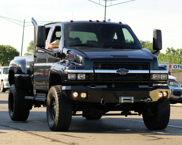 the large black truck is parked on a street