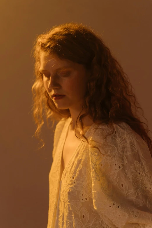 a young woman is standing with her head down looking off