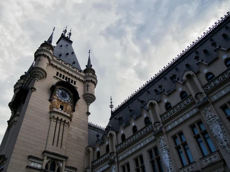 an architectural clock tower with clouds behind it