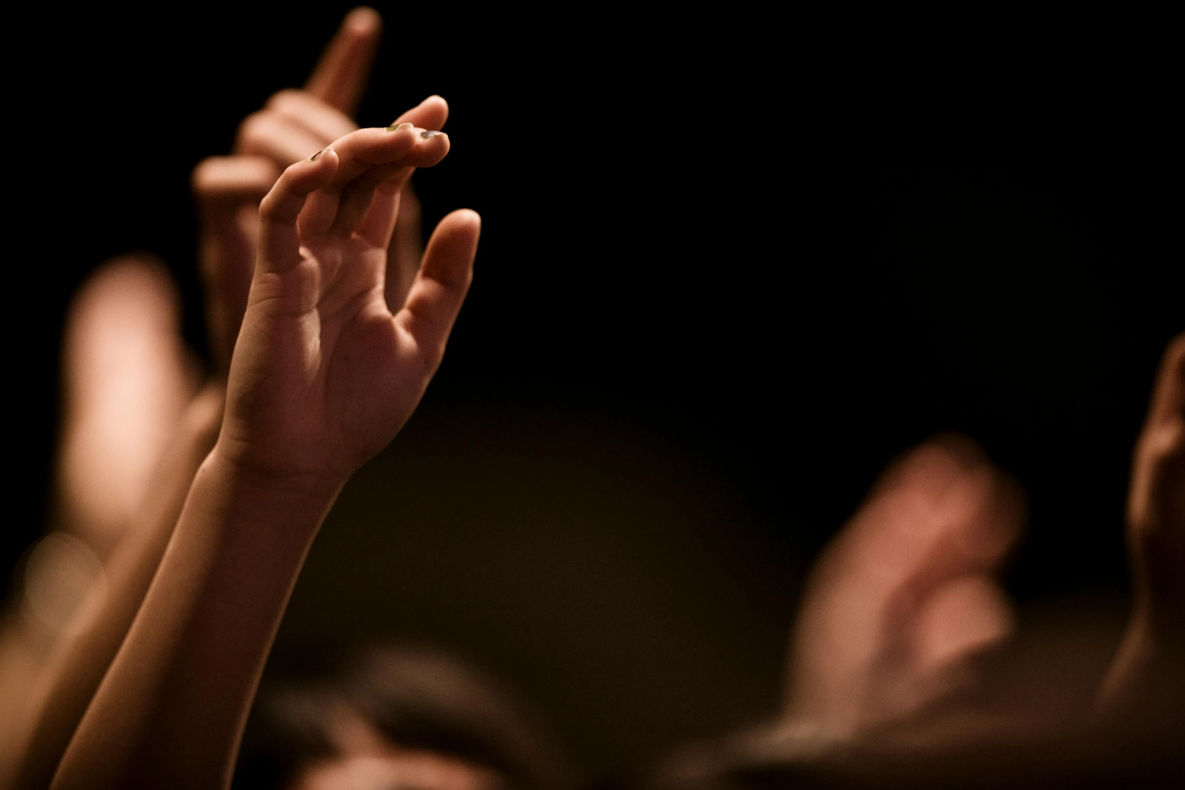 several people in a auditorium are raising their hands